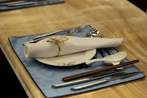 Cutlery and plates on a white background glasses of wine and red rose